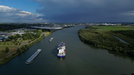 Aerial-panoramic-view-of-river-with-cargo-ships-and-surrounding-flat-landscape