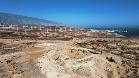Wide-Aerial-Shot-of-Vast-Desert-with-Windmills-Running-in-Background,-Spain