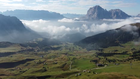 Vista-Aérea-De-Una-Pequeña-Civilización-En-El-Suelo-En-Medio-De-Las-Montañas-De-Dolomitas-Con-La-Niebla-Sobre-Las-Casas