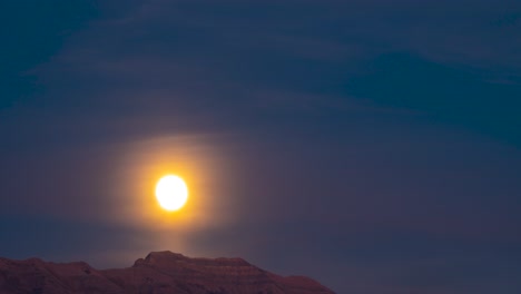 Sunset-to-nightfall-with-the-glowing-full-moon-rising-above-the-mountain-peak---time-lapse
