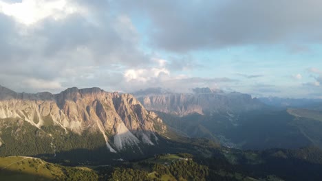 Wide-drone-shot-of-Dolomites-mountains-and-some-forest-around-that-area,-Italy
