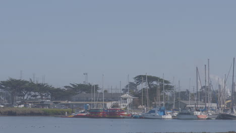Slow-motion-panning-shot-of-sail-boats-docked-in-Moss-Landing-Harbor-California