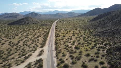 Aerial-drone-shot-flying-through-vast-landscape-of-Anza-Borrego-desert-road-near-Blair-Valley,-California