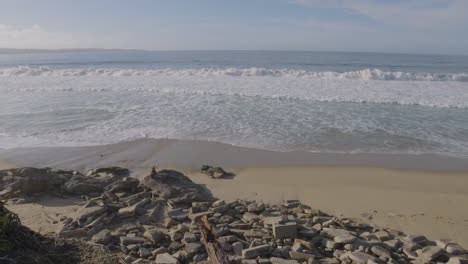 Slow-motion-shot-of-a-rocky-beach-on-a-sunny-day-at-California-Monterey-Bay-Marina-State-Beach