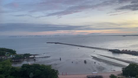 Beautiful-sunrise,-low-tide-sea-view,-houses-and-fishing-boats-mooring-near-Na-Kluea-Fishing-Boat-Pier,-Pattaya,-Thailand