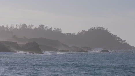 Slow-motion-shot-of-the-ocean-with-foggy-mountains-background-located-in-California-Marina-State-Beach-Monterey-Bay