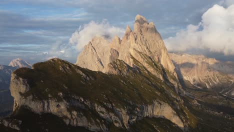 moving-foward-drone-shot-of-top-of-a-mountain-in-a-sunset-with-big-clouds-in-Dolomites,-Italy