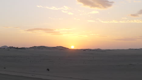 Driving-On-Desert-Road-With-Stunning-View-Of-Sand-Dunes-And-Sun-Setting-Down-In-Background