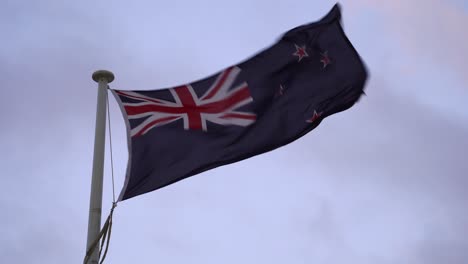 Strong-wind-blowing-New-Zealand-flag,-waving-against-sky-background,-blue-field-with-the-Union-Jack-in-the-canton-and-four-stars,-forming-the-Southern-Cross-constellation