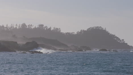 Zeitlupenaufnahme-Von-Wellen,-Die-Auf-Ein-Felsiges-Ufer-Mit-Nebligem-Berghintergrund-Im-Marina-State-Beach-Monterey-Bay-Kalifornien-Krachen