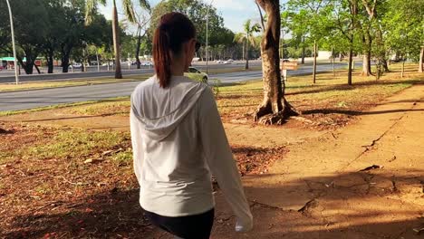 Young-fit-Latina-woman-in-hoodie-exercises-in-urban-area-next-to-busy-street-with-traffic