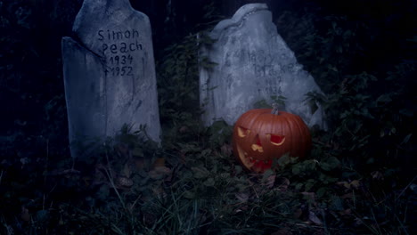 Flammender-Halloween-Kürbis-Und-Grabstein-Auf-Dem-Friedhof,-Blinkendes-Mondlicht-Und-Nebel,-Slider-Mittelaufnahme