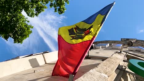 Moldovan-flag-on-house-facade-flagpole-blown-by-wind,-low-angle-shot