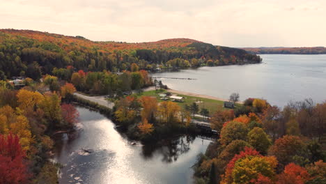 Aerial-shot-of-campground-beside-river-flowing-inside-Algonquin-Provincial-Park,-Canada