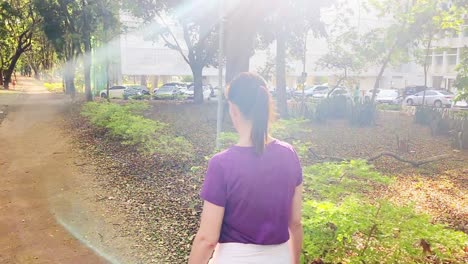 Rear-view-of-woman-leisurely-walking-through-city-on-a-sunny-day