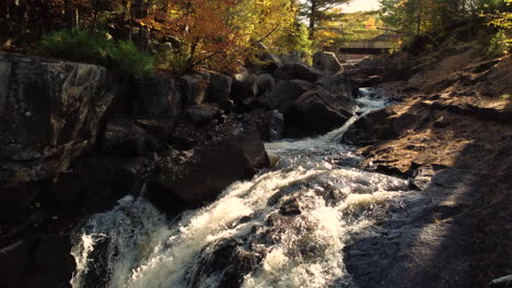 Drohne-Nach-Natürlichem-Wasserfall-Im-Wald-Des-Algonquin-Provincial-Park-Mit-Sonnenlicht,-Das-Auf-Bäume-Und-Wasser-Fällt