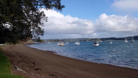 Beautiful-ocean-and-beach-view-with-moored-boats-on-a-sunny-day-at-popular-historic-coastal-small-town-Russell-in-Bay-of-Islands,-New-Zealand-Aotearoa
