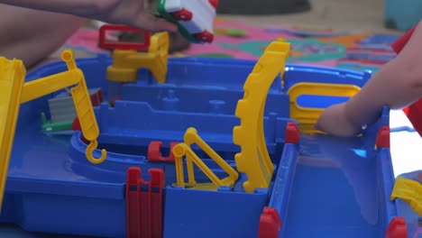 Ansicht-Von-Kindern,-Die-Mit-Wasserspielzeug-Spielen,-Wobei-Ein-Wasser-Aus-Einem-Kleinen-Plastikspielzeugboot-Abfließt