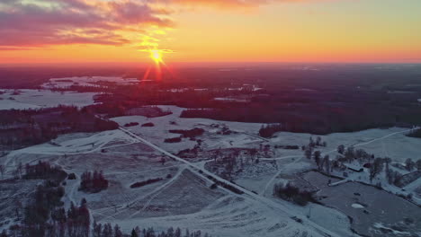 Drohne-Fliegt-über-Schneebedeckte-Waldlandschaft-Mit-Sonnenuntergang-Am-Horizont