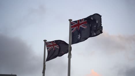 Flag-of-Australia-and-New-Zealand-waving-side-by-side-against-the-sky,-natural-allies-with-a-strong-trans-Tasman-sense-of-family,-slow-motion-close-up-shot