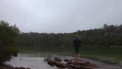 A-man-casts-a-fishing-line-into-a-calm-bay-on-the-far-south-coast-of-NSW-Australia