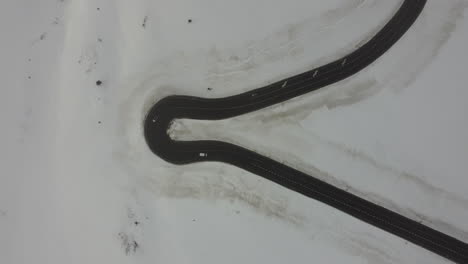 Snowy-white-winter-landscape,-car-drive-sharp-road-turn,-top-down-aerial-view
