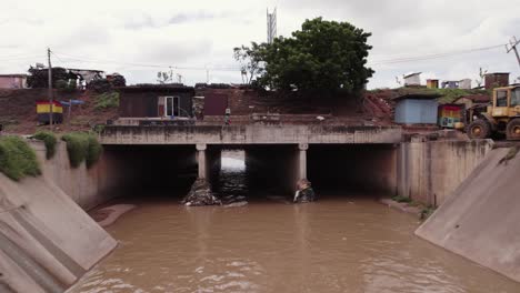 Aerial-Reveal-of-Large-Open-Storm-Drain-with-Sewage-Water-in-Ghana