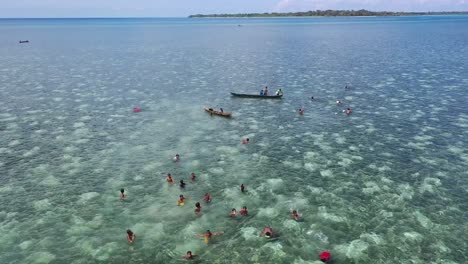 Schöne-Luftaufnahme-Mit-Kindern,-Die-Gerne-Im-Meerwasserdorf-Kampung-Bajau,-Sulawesi,-Indonesische-Kultur-Spielen-Und-Schwimmen