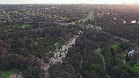Vista-Aérea-Sobre-El-Parque-De-Pisos-De-Yarra-Inundado-Con-Agua-De-Inundación-El-14-De-Octubre-De-2022,-Con-La-Autopista-Oriental-Y-El-Horizonte-De-La-Ciudad-De-Melbourne-En-El-Fondo