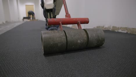 Slow-motion-following-a-metal-roller-that-is-rolling-along-squares-of-carpet