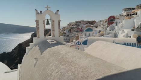 Vertical-pan-and-reveal-of-white-greek-church-bells-with-seaview-in-Santorini,-Greece