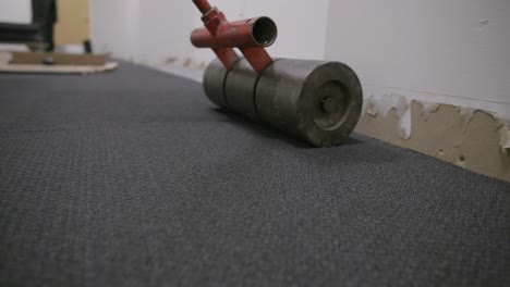 Side-along-the-floor-footage-of-a-roller-going-back-and-forth-along-newly-laid-carpet