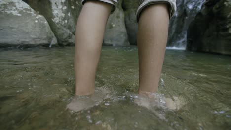 Slow-motion-footage-following-the-feet-of-a-young-african-american-man-as-they-go-through-the-water-of-a-stream