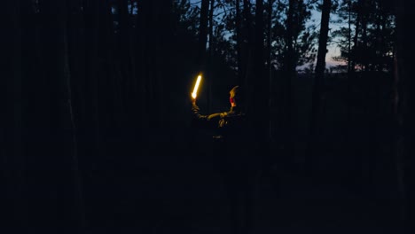 adventurer-with-backpack-and-torch-light-walks-though-dark-forest-searching-the-darkness-at-night