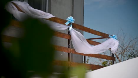 Wooden-balcony-decorated-with-and-white-veil-and-blue-decorations,-wedding-decoration,-outside,-slow-motion