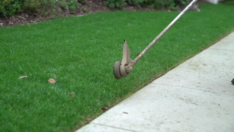 A-gardener-cutting-the-grass,-mowing-the-lawn-with-a-string-machine