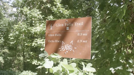 Footage-of-a-nature-sign-that-says-Glenn-Falls-Trail-with-some-graffiti-on-it-in-Chattanooga,-TN