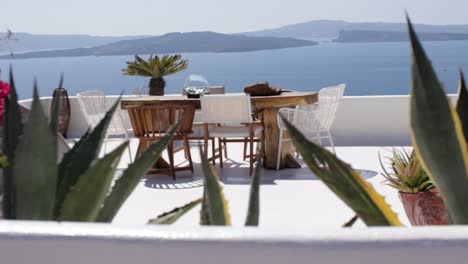 Schwenken-über-Bunte-Blumen-über-Eine-Terrasse-Mit-Meerblick-Und-Möbeln-Im-Freien-In-Santorini,-Griechenland