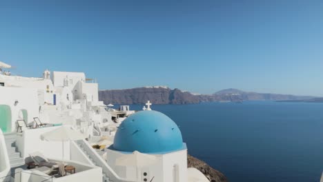 Panorámica-Sobre-La-Iglesia-Griega-Azul-Blanca-Con-Vistas-Al-Mar-En-Santorini,-Grecia