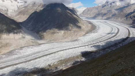 Slow-pan-up-while-flying-towards-the-Aletsch-Glacier,-Switzerland-during-the-day-in-summer