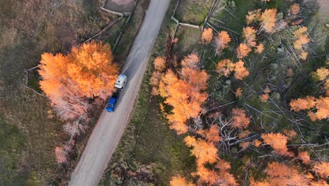 Above-view-showing-a-beautiful-back-road-and-fall-colors-while-a-blue-jeep-and-airstream-roll-through-this-adventure