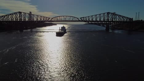 Drone-shot-of-a-cargo-ship-traveling-under-Quebec-bridge
