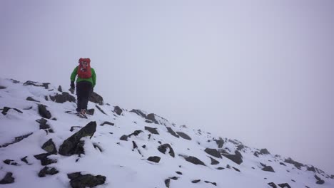 Person-hiking-up-snow-covered-mountain-in-foggy-weather