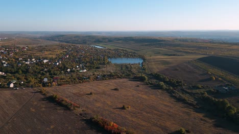 Aerial-drone-flight-in-autumn-of-Codru,-Chisinau,-Moldova-in-2022---colorful-fields-and-trees-with-a-fishing-lake-in-the-center---romantic-places-to-travel-in-the-wine-regions-of-Moldova
