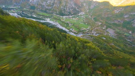 Drone-proximity-flight-down-a-autumn-coloured-mountain-towards-the-village-of-Theth-in-Albania