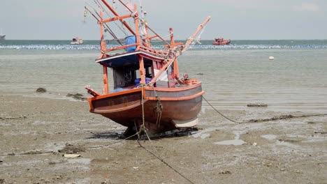 A-tilt-reveal-shot-of-a-moored-beached-Squid-fishing-boat-during-low-tide-in-Thailand