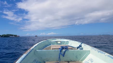 Sitting-in-a-small-motorboat-overlooking-the-front-bow-of-boat-approaching-small,-remote-tropical-island-of-Nahlap-in-Pohnpei,-Micronesia,-over-calm-blue-ocean-on-sunny-day