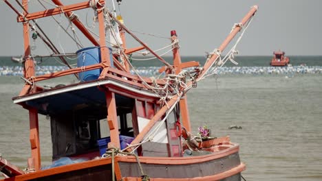 Eine-Nahaufnahme-Eines-Traditionellen-Thailändischen-Tintenfisch-Fischerboots,-Das-Bei-Ebbe-In-Thailand-Festgemacht-Und-Gestrandet-Ist