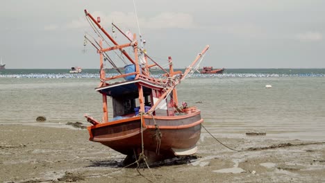 An-establishing-shot-of-a-moored-beached-Squid-fishing-boat-during-low-tide-in-Thailand