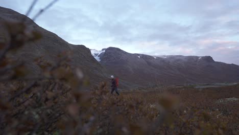 Person-hiking-during-moody-morning-in-valley-between-wild-mountains-in-Norway